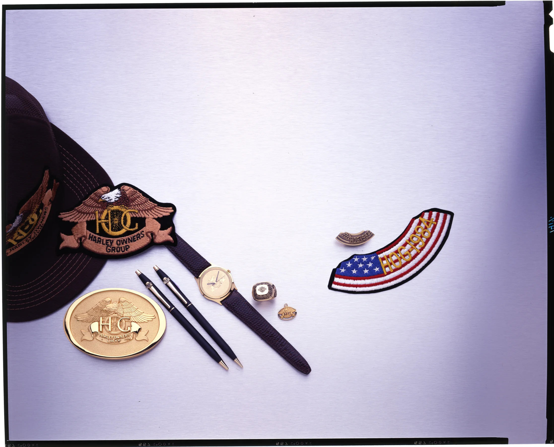 Collage of various HOG memorabilia, including a hat, wristwatch, pin, patches, etc.